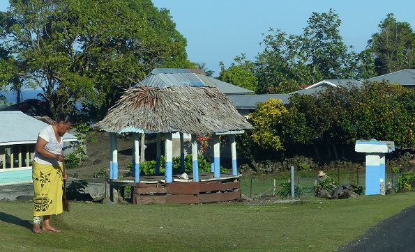 Small fale, rubbish stand, and lady in lavalava